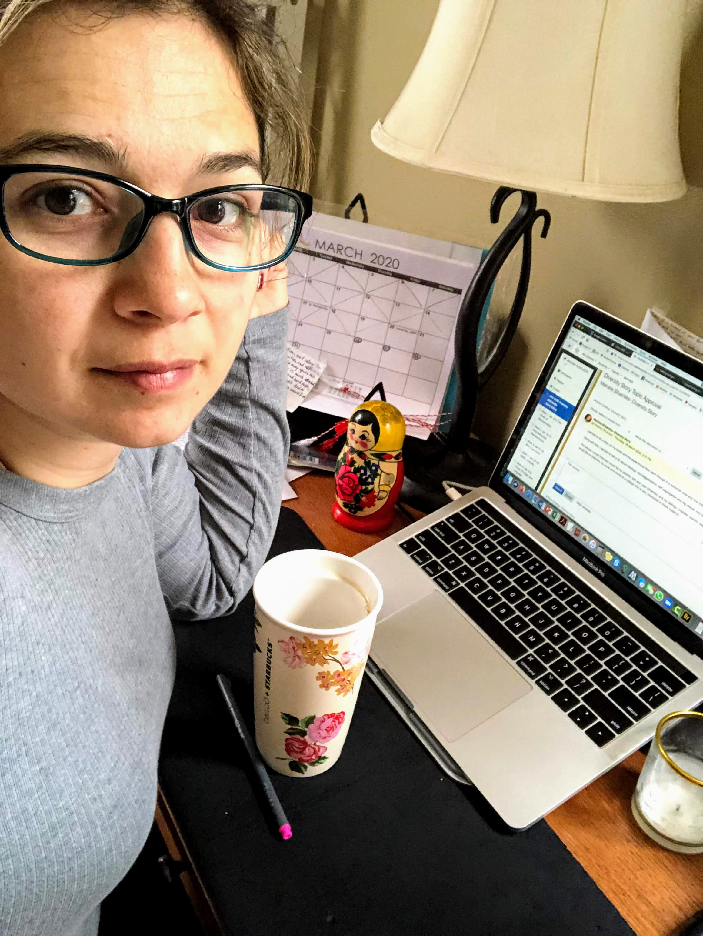Woman in front of laptop, with coffee mug, calendar in the background